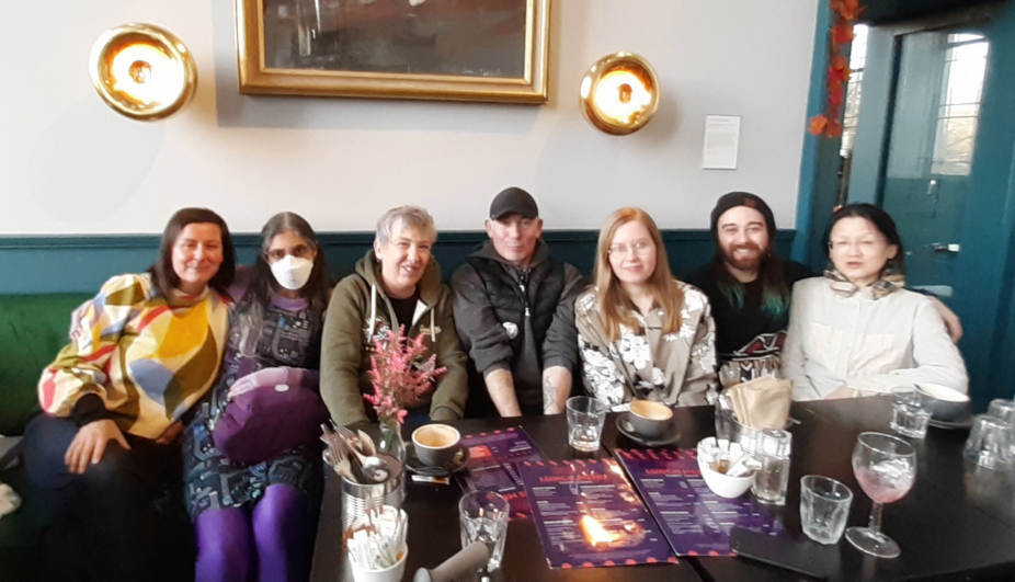 Seven people (the Out of Sight Out of Mind planning group) seated together at a table.